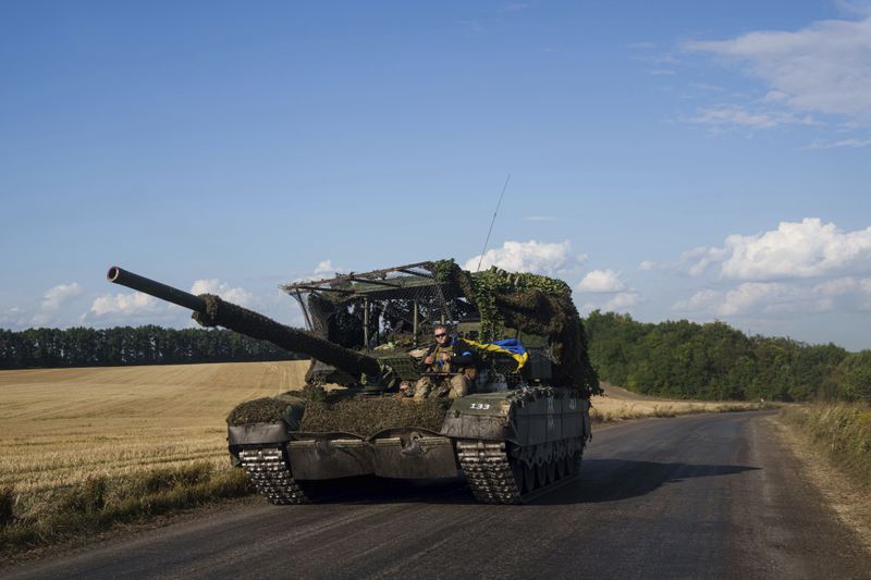 Ukrainian serviceman ride atop a trophy tank after returning from Russia near the Russian-Ukrainian border in Sumy region, Ukraine, Thursday, Aug. 15, 2024. (AP Photo/Evgeniy Maloletka)