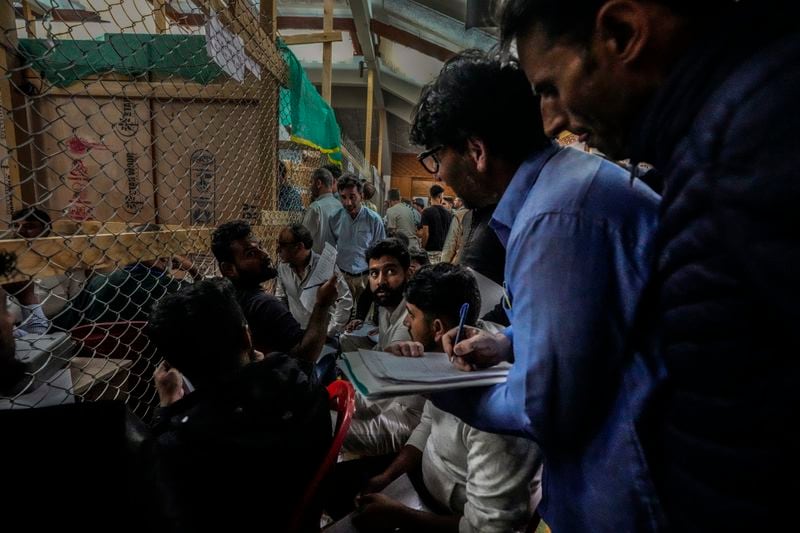 Political party representatives watch as polling officials count the votes in the recent election for a local government in Indian-controlled Kashmir on the outskirts of Srinagar, Tuesday, Oct. 8, 2024. (AP Photo/Mukhtar Khan)