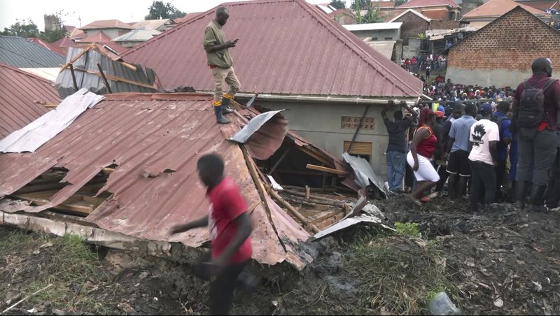 In this photo taken from video people gather at a site of a collapsed landfill in Kampala, Uganda, Saturday, Aug. 10, 2024. At least 18 people were killed after a landfill collapsed late Friday in the Ugandan capital, according to the Red Cross. (AP video via AP)