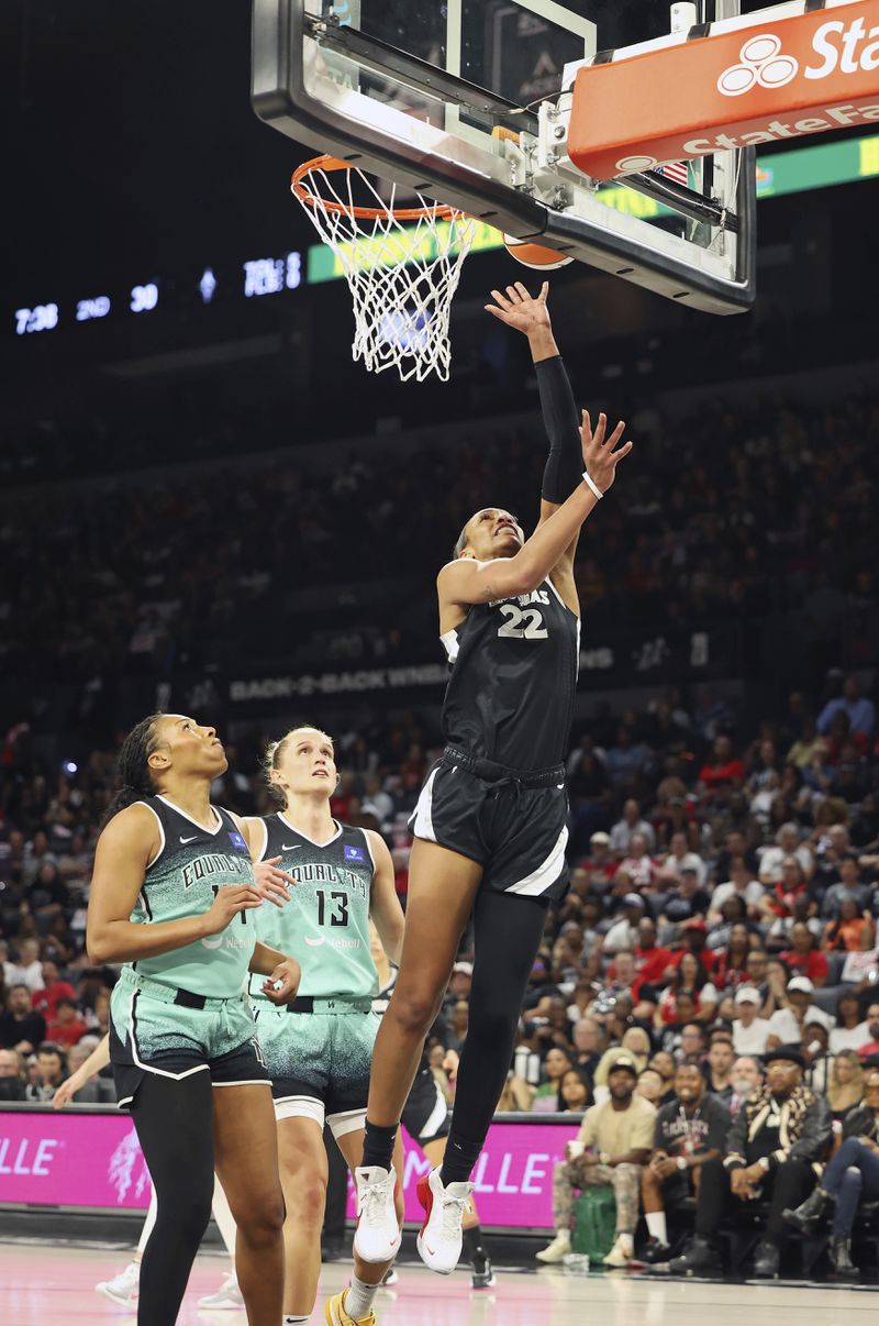 Las Vegas Aces center A'ja Wilson (22) shoots the ball near New York Liberty's Betnijah Laney-Hamilton (44) and Leonie Fiebich (13) during a WNBA basketball semifinal game, Friday, Oct. 4, 2024, in Las Vegas. (AP Photo/Ronda Churchill)