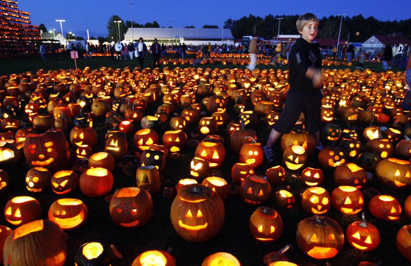 FILE - A boy finishes lighting a patch of jack-o-lanterns at the Camp Sunshine Maine Pumpkin Festival, Oct. 4, 2008, in Cumberland, Maine. (AP Photo/Robert F. Bukaty, File)