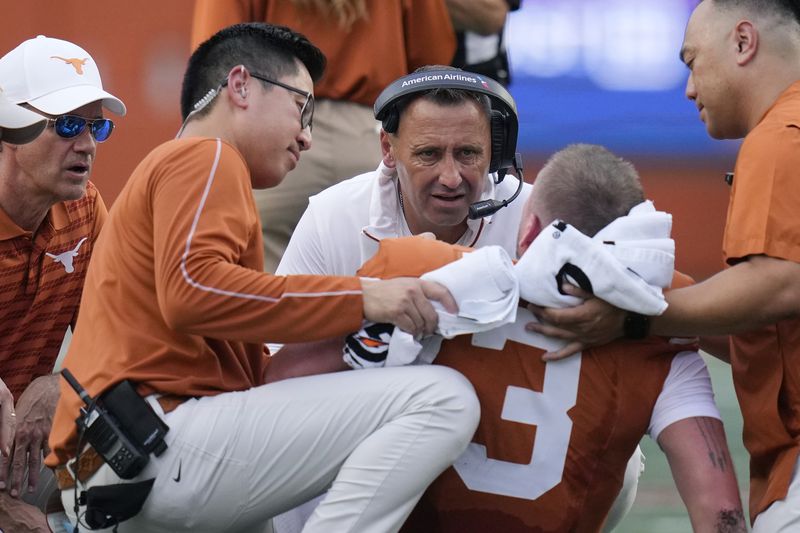 Texas head coach Steve Sarkisian, center, checks on quarterback Quinn Ewers (3) after an injury during the first half of an NCAA college football game against UTSA in Austin, Texas, Saturday, Sept. 14, 2024. (AP Photo/Eric Gay)