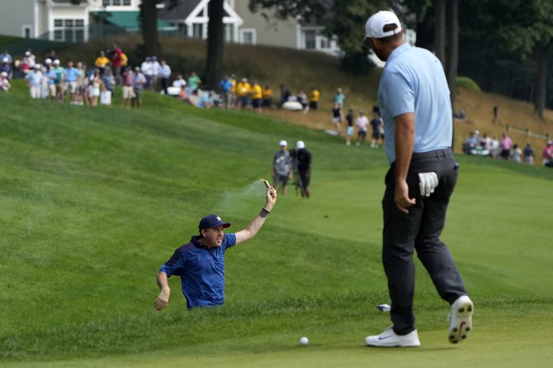 A protester runs onto the course as Scottie Scheffler, right, watches on the 18th hole during the final round of the Travelers Championship golf tournament at TPC River Highlands, Sunday, June 23, 2024, in Cromwell, Conn. (AP Photo/Seth Wenig)