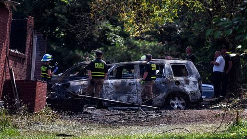 A firefighter inspects a burnt car from a house fire in Newnan, Ga. on June 17. (Ziyu Julian Zhu/Atlanta Journal-Constitution via AP)