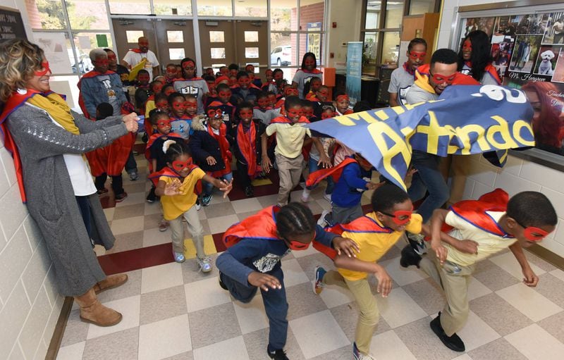 Students break the finish-line banner as they run around the hallways at Miles Elementary School on Friday, Nov. 22, 2019. On Fridays, Miles Elementary School rewards students with good attendance by holding a run around the school hallways. HYOSUB SHIN / HYOSUB.SHIN@AJC.COM