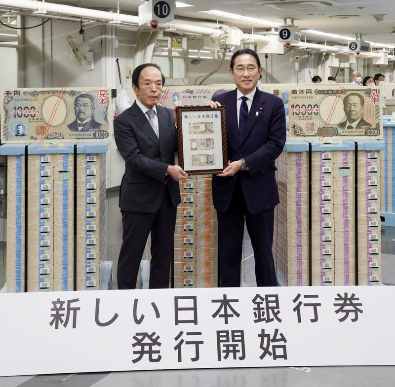 Japanese Prime Minister Fumio Kishida, right, and Bank of Japan Governor Kazuo Ueda hold the country’s new banknotes in a frame, during a ceremony to mark the release of the banknotes, at the BOJ headquarters in Tokyo, Japan, Wednesday, July 3, 2024. The words at bottom read: New Bank of Japan banknotes start being issued. (Japan Pool/Kyodo News via AP)