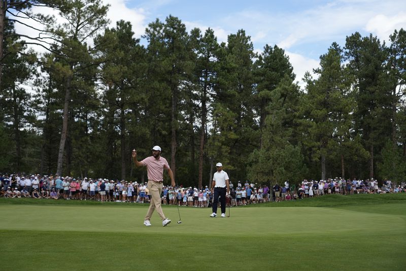 Scottie Scheffler, center left, waves to the gallery on the 14th green during the second round of the BMW Championship golf event at Castle Pines Golf Club, Friday, Aug. 23, 2024, in Castle Rock, Colo. (AP Photo/Matt York)