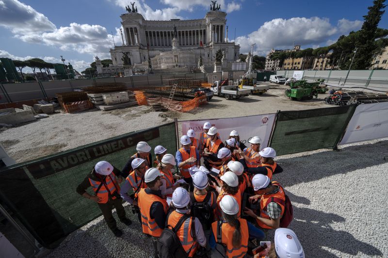 Chief engineer Andrea Sciotti, center, technical director for Rome's new 25.5-kilometer Metro C subway talks to international journalists at the construction site of line C main hub in central Rome, Thursday, May 23, 2024. During a tour Thursday of the construction site at Piazza Venezia, Sciotti said works on the nearly 3 billion euro project, considered one of the most complicated in the world, were running at pace to be completed by 2034. In the background the Unknown Soldier monument. (AP Photo/Domenico Stinellis)