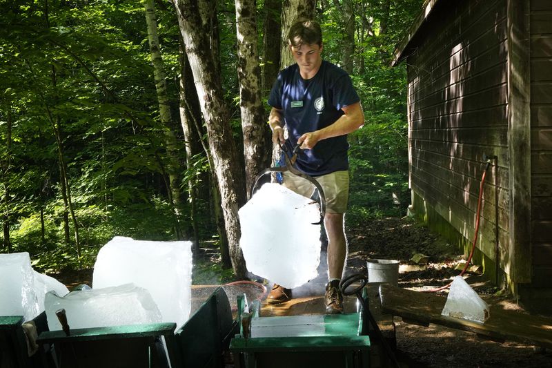 Will McLane loads a block of ice onto a wheelbarrow at Rockywold Deephaven Camps, Thursday, June 20, 2024, in Holderness, N.H. Ice harvested from the lake in winter is used to refrigerate guest's ice boxes throughout the summer season. (AP Photo/Robert F. Bukaty)