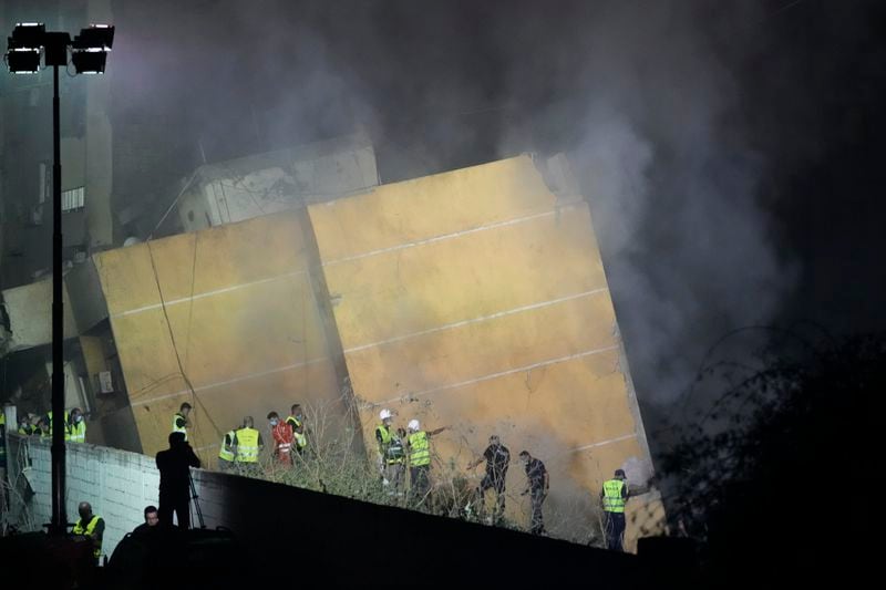 Rescuers gather as smoke rises from a collapsed building at the site of an Israeli airstrike in Beirut's southern suburbs, Friday, Sept. 27, 2024. (AP Photo/Hassan Ammar)