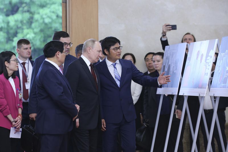 Vietnamese Prime Minister Pham Minh Chinh, front left, and Russian President Vladimir Putin, front center, look at photos displayed at the government office in Hanoi, Vietnam Thursday, June 20, 2024. (Luoung Thai Linh/Pool Photo via AP)