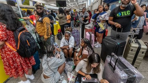 Torry Wallace (right) waits with his stepdaughter’s friends and family on the North Terminal for a flight to Las Vegas for her birthday party as a massive outage is affecting Microsoft users around the globe, disrupting airlines, railways, banks, stock exchanges and other businesses. (John Spink/AJC)