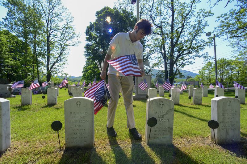 Hudson Buckley, a high school student in Brattleboro, Vt., placed an American flag at the gravesite of a veteran at a local cemetery on Wednesday. 