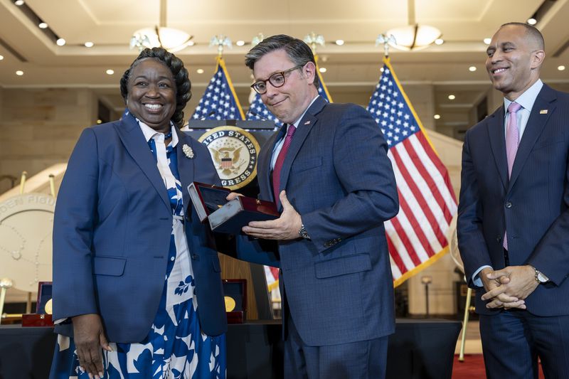 House Speaker Mike Johnson, R-La., reacts after dropping a Congressional Gold Medal while posing for a photograph with NASA's Johnson Space Center Senior Apollo Sample Processor and Lab Manager Andrea Mosie, left, at a Congressional Gold Medal ceremony to honor the Black women mathematicians of NASA who contributed to the space race and who were the subject of the book and movie "Hidden Figures," at the Capitol in Washington, Wednesday, Sept. 18, 2024. House Minority Leader Hakeem Jeffries, D-N.Y., watches at right. (AP Photo/J. Scott Applewhite)