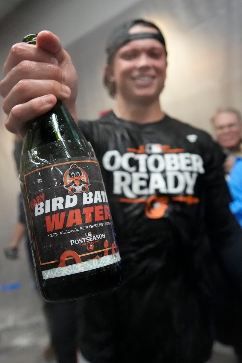 Baltimore Orioles' Jackson Holliday holds a bottle of a nonalcoholic beverage during post-game celebrations after the team clinched a playoff berth by defeating the New York Yankees in baseball game, Tuesday, Sept. 24, 2024, in New York. Holliday is the only member of the Orioles not of legal drinking age. (AP Photo/Bryan Woolston)