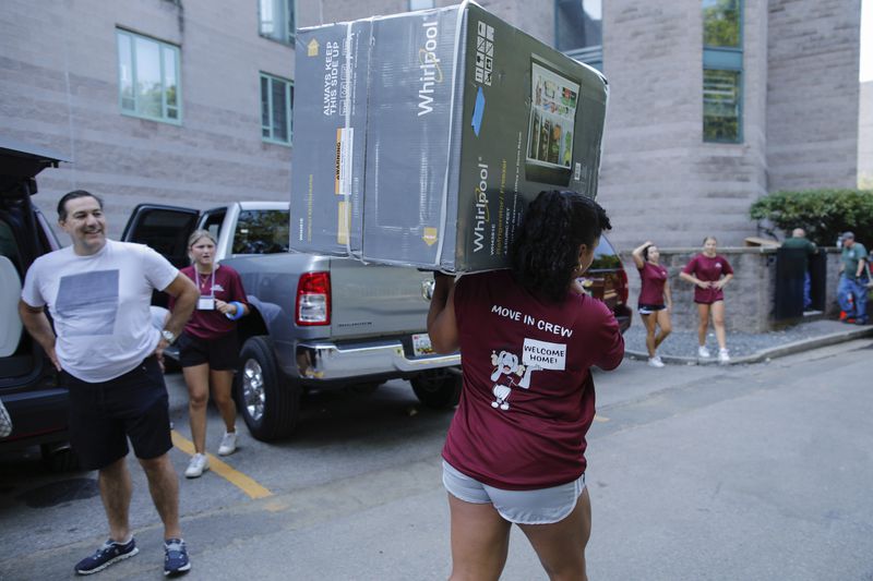 A student carries a refrigerator as New students arrive during Move In Day at the Bronx campus, Sunday, Aug. 25, 2024, in New York. (AP Photo/Kena Betancur)