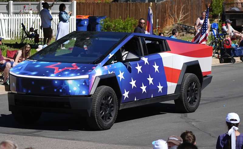 A Tesla Cybertruck wrapped in patriotic motif rolls along in the Colorado 4th at Firestone parade to mark the Independence Day holiday Thursday, July 4, 2024, in Firestone, Colo. Floats, marching bands, classic cars and motorcycles were features in the annual parade through the Weld County community north of Denver. (AP Photo/David Zalubowski)