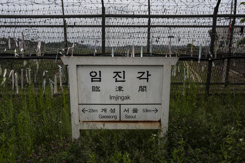 A directional sign showing the distance to North Korea's Kaesong and Seoul stands in front of fences adorned with ribbons bearing messages wishing for the reunification of the two Koreas at the Imjingak Pavilion in Paju, South Korea, Saturday, May 25, 2024. (AP Photo/Jae C. Hong)