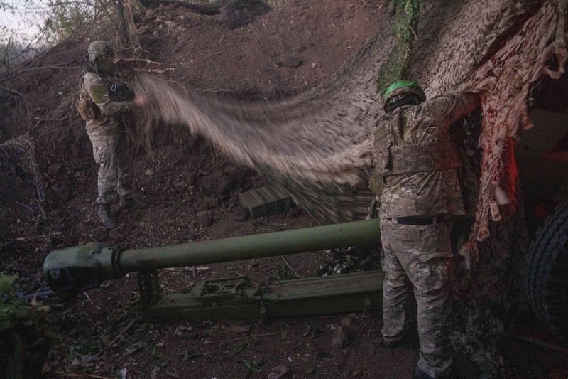 Ukrainian servicemen of Liut brigade camouflage D-30 artillery cannon after firing towards Russian position near Toretsk, Donetsk region, Ukraine, Sunday Sept. 22, 2024. (AP Photo/Evgeniy Maloletka)