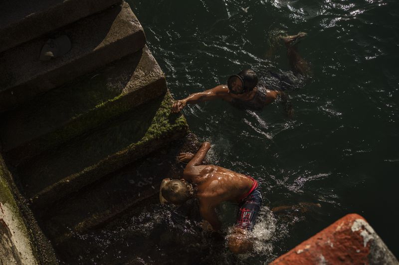 Rafael Murillo, a diver, left, swims with a colleague in the sea in Veracruz, Mexico, Saturday, June 15, 2024. Victims in Veracruz have made up nearly a third of Mexico's heat-related deaths as temperatures have reached 100 degrees in the humid Mexican gulf state. (AP Photo/Felix Marquez)