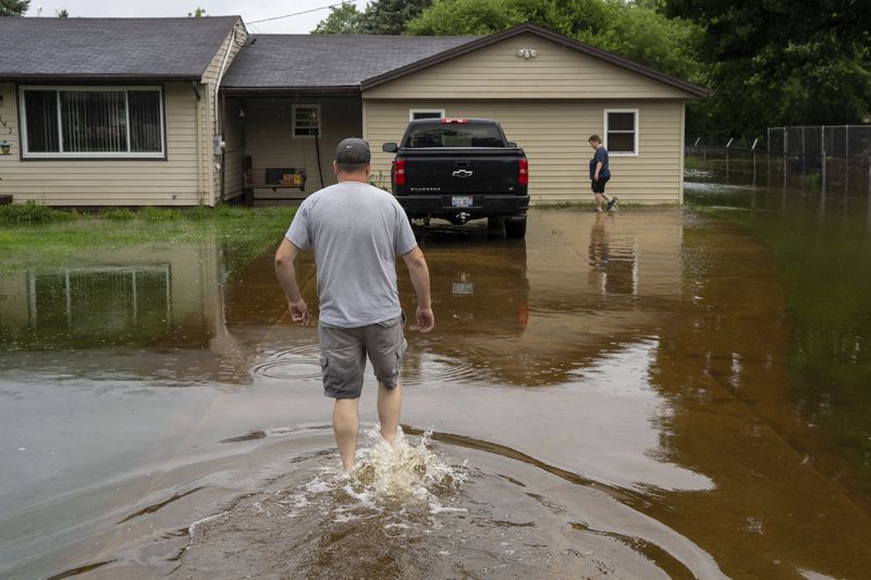 Ken Doyka, and his wife, Ginger Doyka walk through their flooded front yard as rains from the remnants of Hurricane Beryl fall, Wednesday, July 10, 2024, in Genesee Charter Township, Mich. (Julian Leshay Guadalupe/The Flint Journal via AP)