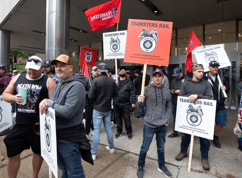 Rail workers picket in front of Canadian National headquarters on the first day of a nationwide rail shutdown, after workers were locked out by CN and CPKC when new contract agreements weren't reached by the midnight deadline, in Montreal, Thursday, Aug. 22, 2024. (Ryan Remiorz /The Canadian Press via AP)