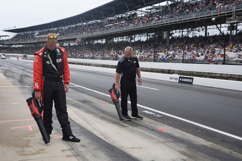 The crew for Will Power, of Australia, dry the pit box before the Indianapolis 500 auto race at Indianapolis Motor Speedway, Sunday, May 26, 2024, in Indianapolis. (AP Photo/Darron Cummings)