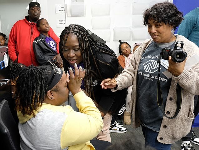 Cynthia Risper-Jett is comforted by Cherene Williams, right, and Dedra Evans, center, after learning that they have a gift card to spend at Academy. Carson Beck was on site at an Athens Academy store Sunday December 17, 2023, to give out gift cards to lucky members of area Boys and Girls Clubs. Academy contributed $200 for each child and he kicked in $135 more of his own money to help families out. 
credit: Nell Carroll for the AJC