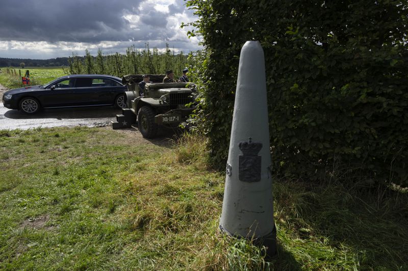 A border marker is seen as Dutch King Willem-Alexander and Queen Maxima arrive by limousine to join World War II veteran Kenneth Thayer, waiting in a jeep, during a ceremony marking the 80th anniversary of the liberation of the south of the Netherlands in Mesch, Thursday, Sept. 12, 2024. (AP Photo/Peter Dejong, Pool)