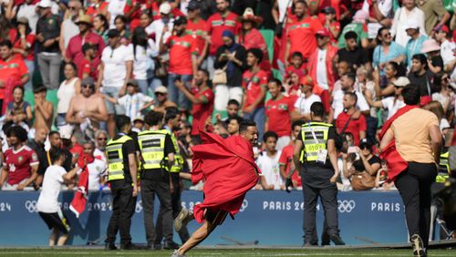 Invaders run on the pitch during the men's Group B soccer match between Argentina and Morocco at Geoffroy-Guichard Stadium at the 2024 Summer Olympics, Wednesday, July 24, 2024, in Saint-Etienne, France. (AP Photo/Silvia Izquierdo)