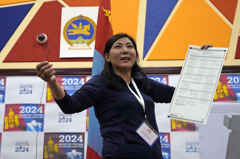 An election worker holds up a ballot as manual counting begins after polls close for parliamentary elections in Ulaanbaatar, Mongolia in the early hours of Saturday, June 29, 2024. Preliminary results were expected by early Saturday morning after voting ended at 10 p.m. Friday across the vast but sparsely populated country squeezed between China and Russia, two much larger authoritarian states. (AP Photo/Ng Han Guan)