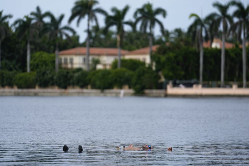 Trump supporter Jestin Nevarez, of Lake Worth, Fla., cools off with a swim in the Lake Worth Lagoon in front of the Mar-a-Lago estate of Republican presidential nominee and former President Donald Trump, one day after an apparent assassination attempt, in Palm Beach, Fla., Monday, Sept. 16, 2024. (AP Photo/Rebecca Blackwell)