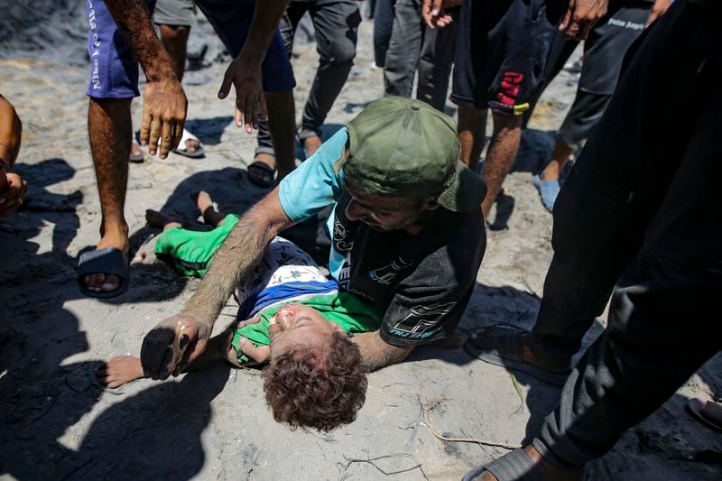 EDS NOTE: GRAPHIC CONTENT - A Palestinian man mourns over the body of his child killed at a site hit by an Israeli bombardment on Khan Younis, southern Gaza Strip, Saturday, July 13, 2024. Israel said it targeted Hamas' shadowy military commander in a massive strike Saturday in the crowded southern Gaza Strip that killed at least 71 people, according to local health officials. Hamas immediately rejected the claim that Mohammed Deif was targeted. (AP Photo/Jehad Alshrafi)