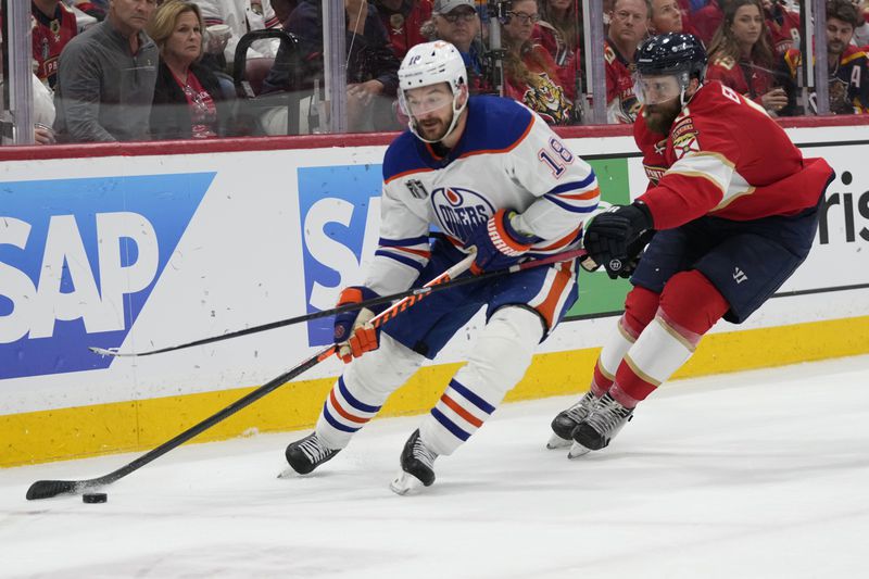 Edmonton Oilers left wing Zach Hyman (18) skates with the puck as Florida Panthers defenseman Aaron Ekblad (5) defends during the third period of Game 5 of the NHL hockey Stanley Cup Finals, Tuesday, June 18, 2024, in Sunrise, Fla. (AP Photo/Wilfredo Lee)