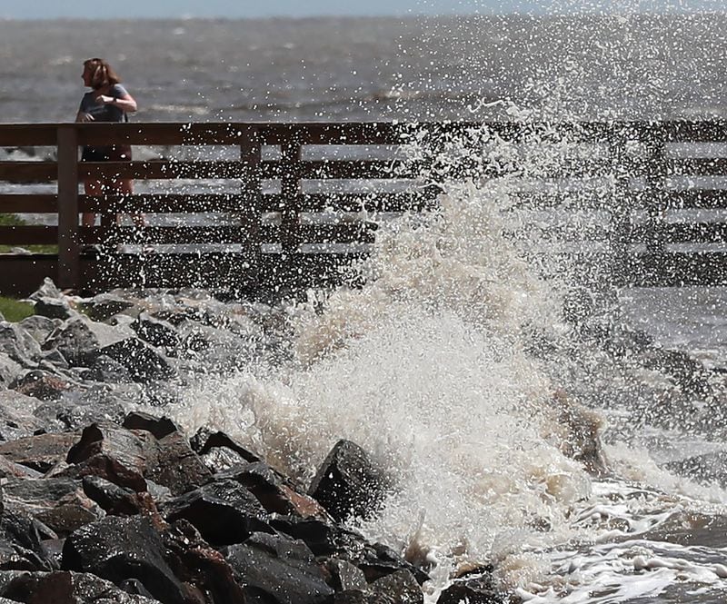 A woman turns away as she gets sprayed by a crashing wave from the outer edge of Hurricane Dorian at St. Simons Island on Sept. 3. CURTIS COMPTON / CCOMPTON@AJC.COM