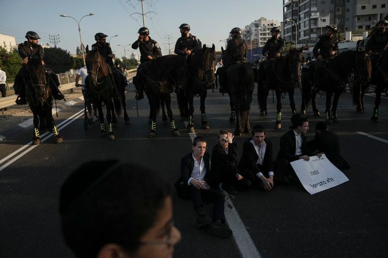 Israeli mounted police officers stand in line as ultra-Orthodox Jews block a highway during a protest against army recruitment in Bnei Brak, Israel, Thursday, June 27, 2024. Israel's Supreme Court unanimously ordered the government to begin drafting ultra-Orthodox Jewish men into the army — a landmark ruling seeking to end a system that has allowed them to avoid enlistment into compulsory military service. (AP Photo/Oded Balilty)