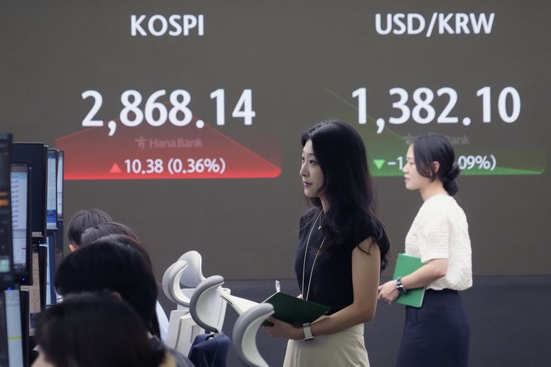 A currency trader watches monitors near the screen showing the Korea Composite Stock Price Index (KOSPI), left, and the foreign exchange rate between U.S. dollar and South Korean won at the foreign exchange dealing room of the KEB Hana Bank headquarters in Seoul, South Korea, Tuesday, July 9, 2024. (AP Photo/Ahn Young-joon)
