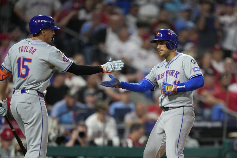 New York Mets' Jose Iglesias, right, and Tyrone Taylor celebrate after Iglesias scored on a sacrifice fly by Starling Marte during the eighth inning of Game 1 of a baseball NL Division Series, Saturday, Oct. 5, 2024, in Philadelphia. (AP Photo/Matt Slocum)