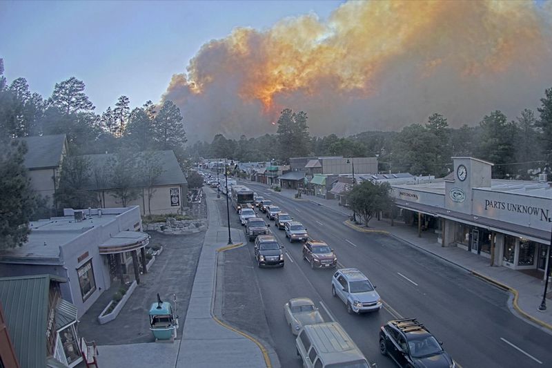 In this image taken from webcam footage provided by the Village of Ruidoso, smoke rises behind Ruidoso, N.M., on Monday, June 17, 2024. Thousands of southern New Mexico residents fled the mountainous village as a wind-whipped wildfire tore through homes and other buildings. (Village of Ruidoso Tourism Department via AP)