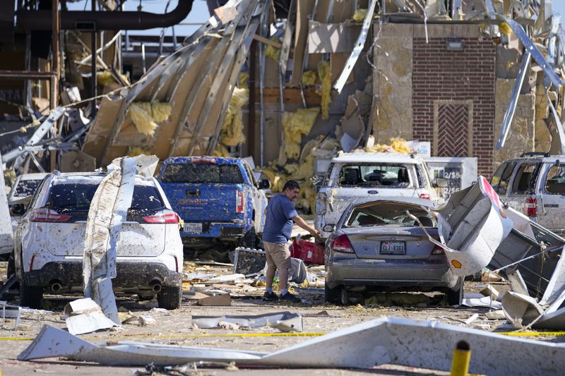 A man looks at a damaged car after a tornado hit the day before Sunday, May 26, 2024, in Valley View, Texas. Powerful storms left a wide trail of destruction Sunday across Texas, Oklahoma and Arkansas after obliterating homes and destroying a truck stop where drivers took shelter during the latest deadly weather to strike the central U.S. (AP Photo/Julio Cortez)