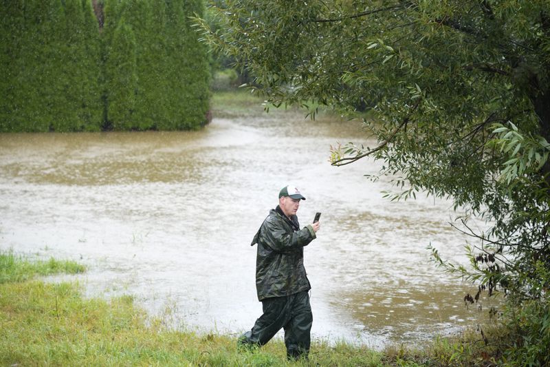 A residents takes a photo as the Opava river rises near Brantice, Czech Republic, Saturday, Sept. 14, 2024. (AP Photo/Petr David Josek)