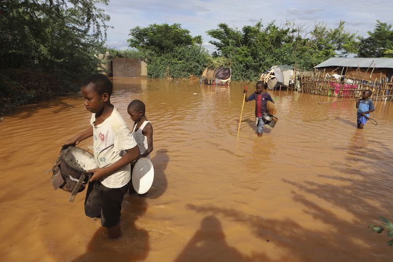 FILE - Children flee floodwaters that wreaked havoc at Mororo, border of Tana River and Garissa counties in North Eastern Kenya, April 28, 2024. The impact of the calamitous rains that struck East Africa from March to May was intensified by a mix of climate change and rapid growth of urban areas, an international team of climate scientists said in a study. (AP Photo/Andrew Kasuku, File)