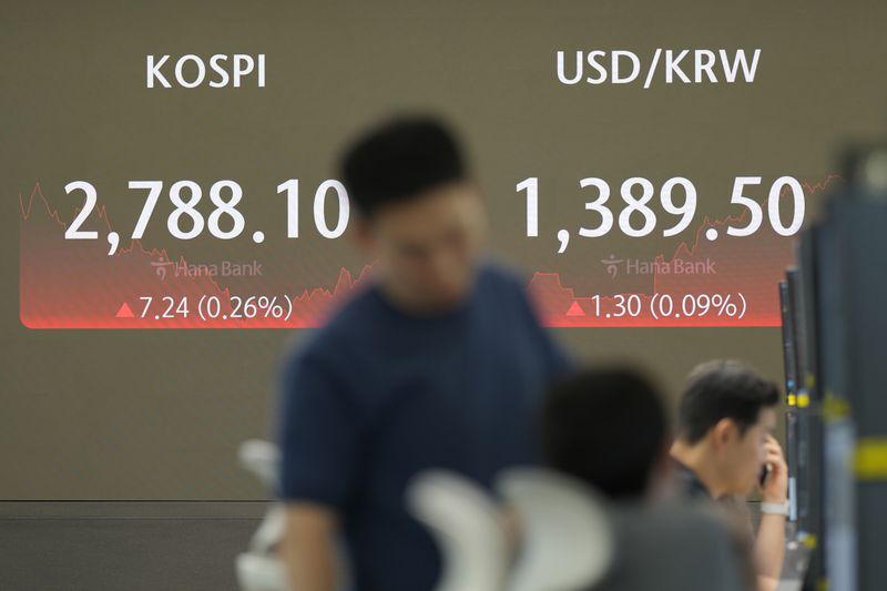 A currency trader stands by the screen showing the Korea Composite Stock Price Index (KOSPI), left, and the foreign exchange rate between U.S. dollar and South Korean won at a foreign exchange dealing room in Seoul, South Korea, Wednesday, July 3, 2024. Asian shares were mostly higher on Wednesday after Tesla gained more than 10%, helping to drive U.S. benchmarks to more records. (AP Photo/Lee Jin-man)