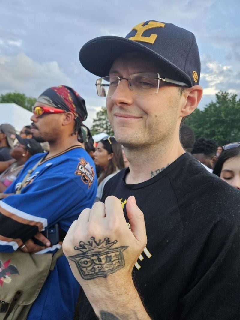 Toronto native Aaron Gwynn shows off the OutKast logo tattooed on his left hand before Andre 3000 performs at the Atlanta Jazz Festival on May 27, 2024.