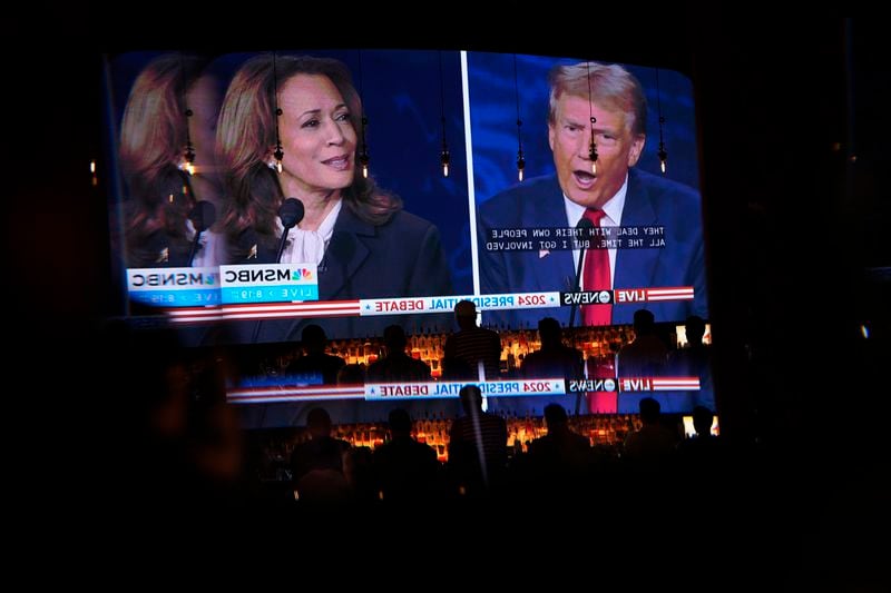 Reflected in a mirror, people watch the presidential debate between Republican presidential nominee former President Donald Trump and Democratic presidential nominee Vice President Kamala Harris, Tuesday, Sept. 10, 2024, at the Gipsy Las Vegas in Las Vegas. (AP Photo/John Locher)