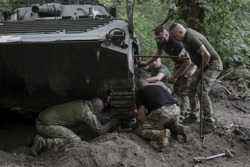 In this photo provided by Ukraine's 24th Mechanised Brigade press service, servicemen of 24th mechanised brigade repair tracks of a BRM1k infantry fighting vehicle near Chasiv Yar town, in Donetsk region, Ukraine, Aug. Saturday 17, 2024. (Oleg Petrasiuk/Ukrainian 24th Mechanised Brigade via AP)