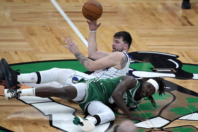 Dallas Mavericks guard Luka Doncic, top, and Boston Celtics guard Jrue Holiday, bottom, land on the parquet as they vie for the ball during the first half of Game 5 of the NBA basketball finals, Monday, June 17, 2024, in Boston. (AP Photo/Charles Krupa)