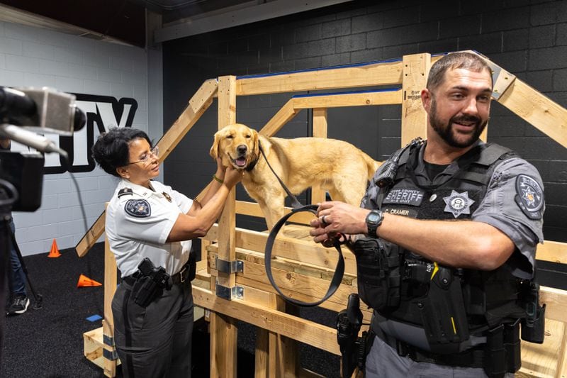 Cobb County police K-9 Sherlock poses for photos with Assistant Chief Gina Hawkins (left) and Deputy Carl Cramer, his handler.