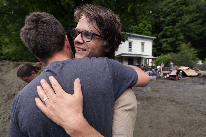 Homeowner Walker Blackwell, right, embraces his friend, Eli Yoder, who just flew out from Colorado to help in the clean up effort, after remnants of Hurricane Beryl caused flooding and destruction, Friday, July 12, 2024, in Plainfield, Vt. (AP Photo/Charles Krupa)