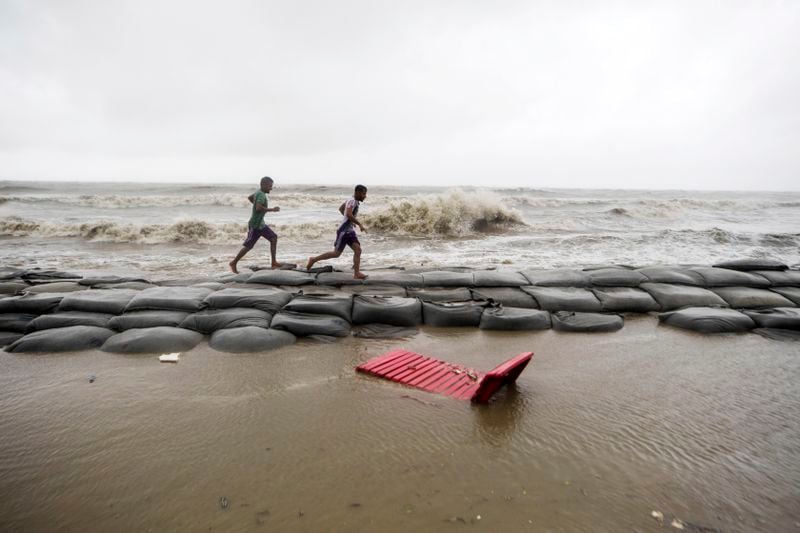 Vendors run to salvage their belongings as strong winds caused by the advancing Cyclone Remal hit the Kuakata beach on the coast of Bay of Bengal in Barisal, Bangladesh, Sunday, May 26, 2024. (AP Photo/Abdul Goni)